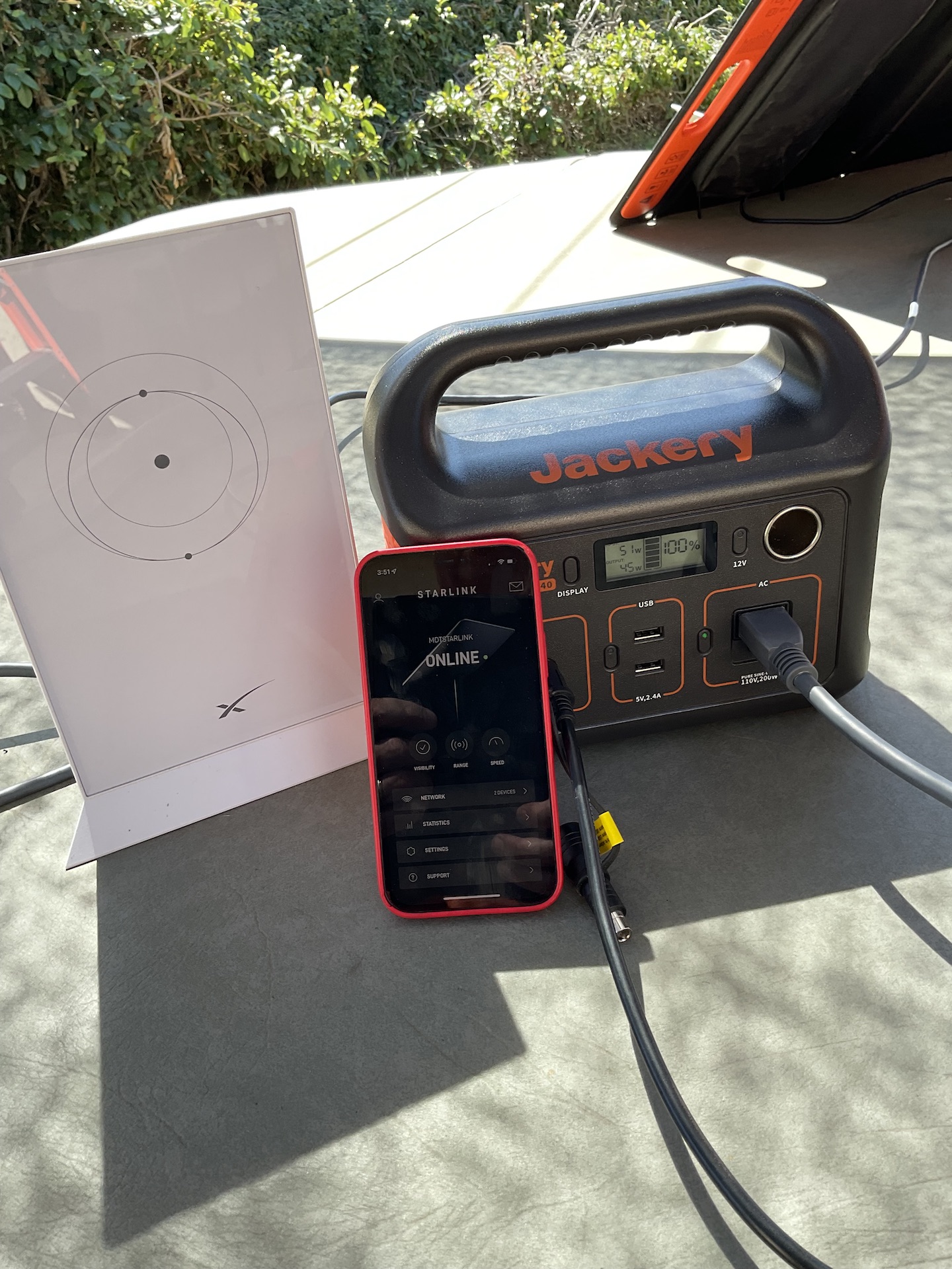 iPhone next to a starlink router and plugged into a 200w Jackery power unit.